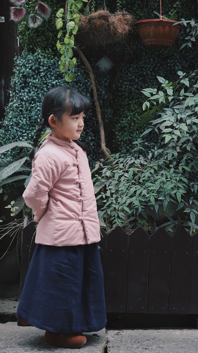 Dressed in a pink jacket girl near the plant
